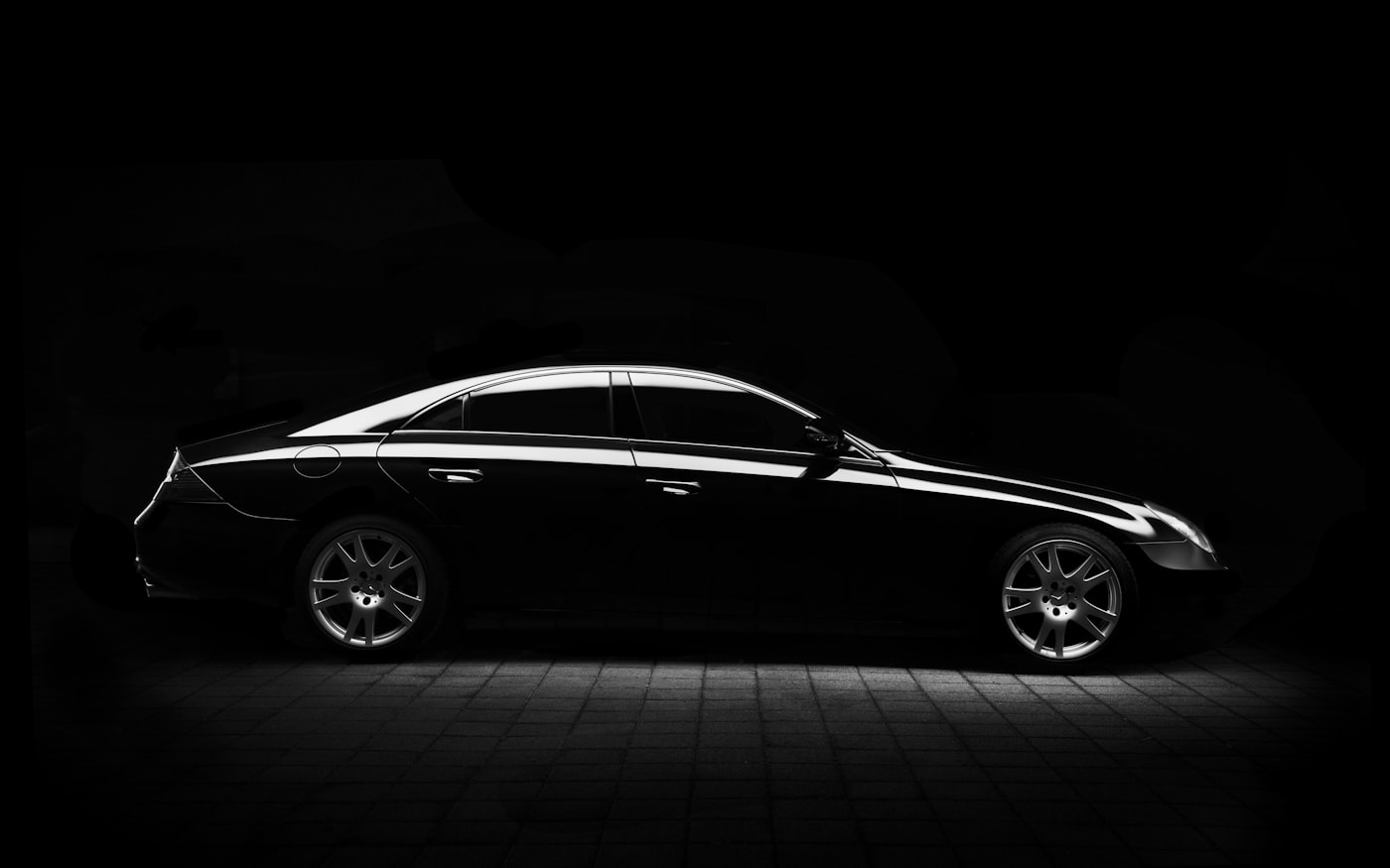 Black executive sedan against a dark studio backdrop